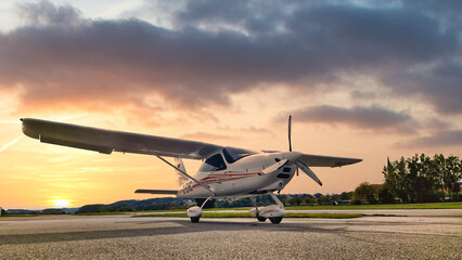 Fototapeta na wymiar Kleinflugzeug auf der Rollbahn eines Landeplatzes mit untergehender Sonne im Hintergrund
