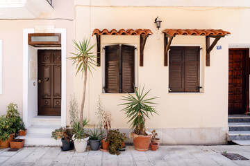 Fototapeta na wymiar Traditional Mediterranean home exterior with wooden shutters and an array of potted plants enhancing the quaint, welcoming vibe