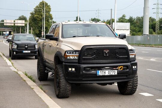 Two Dodge RAM 1500 pickups with large tyres parked on a road