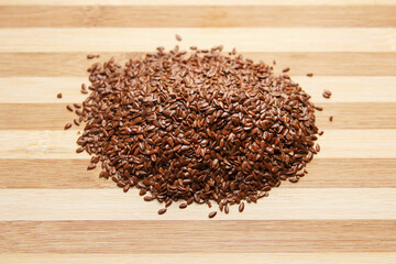 Many linen raw seeds lie on a wooden surface in the kitchen. Top view.