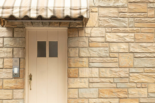 A simple beige doorway entrance into a cobblestone building. This light colored stone wall makes for a seamless background. Bright and geometric backdrop.
