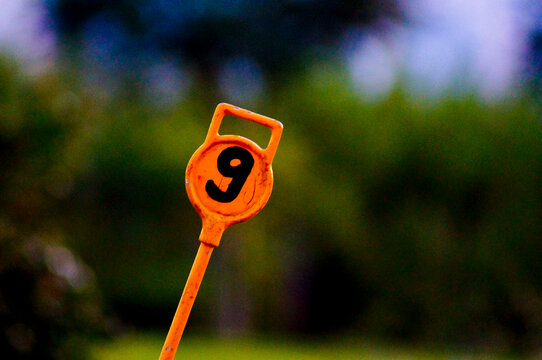 Golf course hole numeric marker. Orange color. Number nine