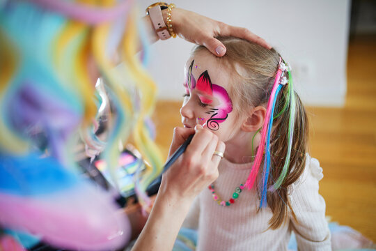 Artist painting little preschooler girl like unicorn on a birthday party. Creative activities for kids