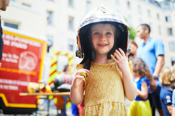 preschooler girl acting like a fireman and wearing a protective helmet