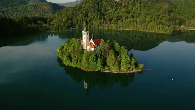 Aerial around view of Bled lake with the Pilgrimage Church of the Assumption of Maria on a small island in morning light, Slovenia, 4k
