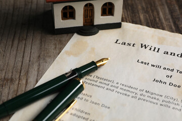 Last Will and Testament with fountain pen and house model on wooden table, closeup