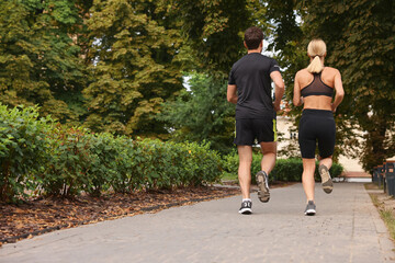 Healthy lifestyle. Couple running in park, back view with space for text