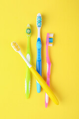 Different toothbrushes on yellow background, flat lay