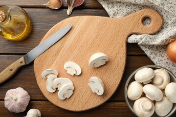 Cutting board with mushrooms and knife on wooden table, flat lay