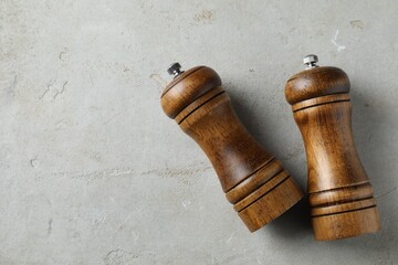 Wooden salt and pepper shakers on light textured table, top view. Space for text