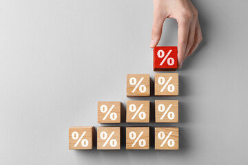 Best mortgage interest rate. Woman putting red cube with percent sign to others on light...