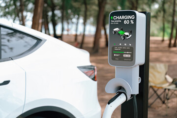 Electric car recharging battery at outdoor EV charging station at natural vacation campsite,...
