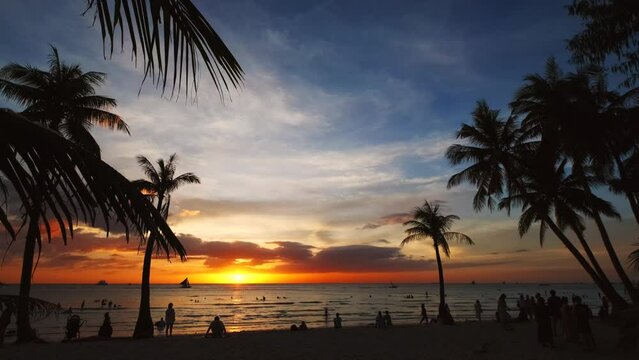 Silhouetted people and palms near sea. Sunset at tropical White beach, Boracay island, Philippines, slow motion 4k
