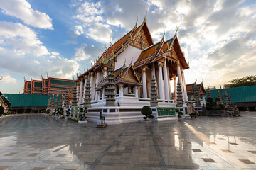 Fototapeta premium Wat Suthat in Bangkok, Thailand. Royal Temple constructed in 1807. Polished Marble floor in foreground; blue sky, sunlit clouds overhead. 