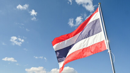 A Thailand national flag blowing by wind against blue sky.