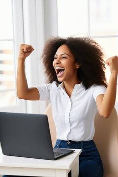 Black woman celebrating in front of laptop