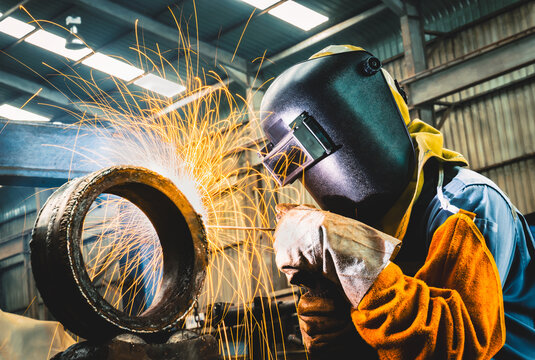 Industrial welder welding fabricated construction in factory, Welding process by Shielded Metal Arc Welding (SMAW) or Stick Welding.