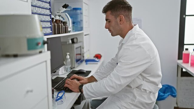 Serious young hispanic male scientist engrossed in high-tech research on computer at modern laboratory, delving into the world of medicine and biology