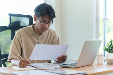 Smiling young businessman checking schedule, planning workday at his office desk.