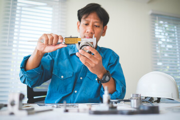 Mechanical engineer working with blueprints and using vernier caliper  to measuring bearings.