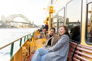 Happy Asian woman friends sitting on ferry boat crossing Sydney harbour in Australia. Attractive...