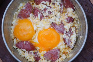 fried egg mixed with sausage in a pan 