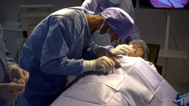 Professional surgical team to operate female patient under anesthesia on bed