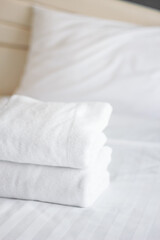 Fototapeta na wymiar Stack of white towels on bed in hotel