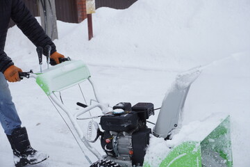 A man cleans snow in the winter in the courtyard of the house,  man cleaning snow with a snow blower