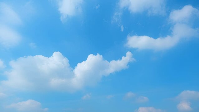 In a fleeting time-lapse, the tranquil blue sky evolves gently, as cotton-like clouds gracefully drift, a serene ballet unfolding overhead. Nature background. Blue sky timelapse.
