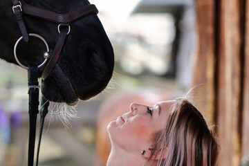 Girl blonde in blue quilted vest with ponytail plays with her horse, portraits of the woman with...