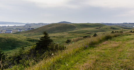 Fototapeta na wymiar vue sur la vallé à partir du sommet d'une colline dans les iles avec du gazon vert au sol lors d'une journée ennuagée