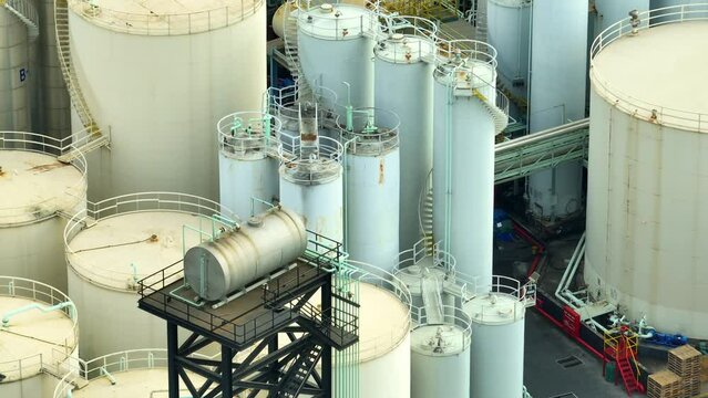 A sprawling lubricant plant glistens like a metallic oasis from above, with rows of gleaming tanks and pipes stretching into the horizon. Video clips.
