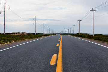 vue sur une route en asphalte grise avec deux lignes jaunes lors d'une journée d'été ennuagée