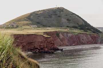 vue sur une colline recouverte de gazon vert avec une falaise à roche rouge en bord de mer