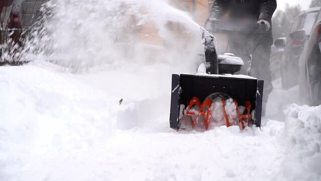 the janitor removes snow with a snow plow in the yard of the house