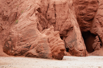 vue sur la paroi d'une falaise en roche rouge avec du sable au sol lors d'une journée d'été ensoleillée - obrazy, fototapety, plakaty