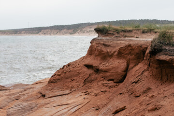 vue sur une falaise en roche rouge au bord de la mer avec du gazon sur le dessus en été lors d'une journée ensoleillée