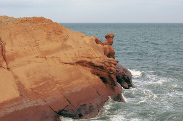 vue sur un rocher rouge en bord de l'eau en été avec des vagues dans la mer