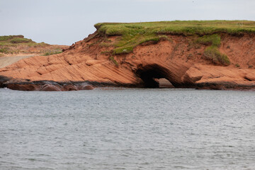 vue sur un rocher en roche rouge au bord de la mer recouvert de gazon vert en été lors d'une journée ensoleillée