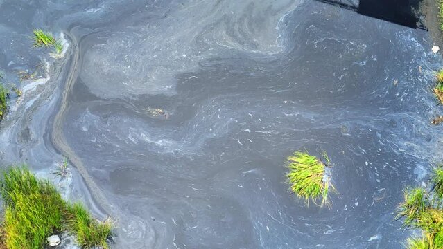 Industrial wastewater is a major water pollution source due to harmful chemicals and toxins discharged during manufacturing. Surface water pollution and microplastics concept. Aerial view.
