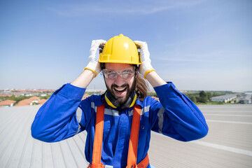 Stressed engineer grab his head suffer from acrophobia while working on the factory rooftop - obrazy, fototapety, plakaty