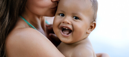 Close up portrait of mother hugging multiracial baby. Mom hug Biracial child. Closeup face of...