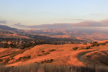 The last rays of the sun shine through the deepening clouds of the coastal fog and marine layer moving inland