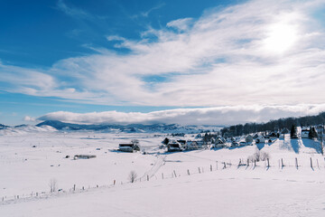 Fototapeta na wymiar Snow-covered village in a mountain valley in bright sunshine