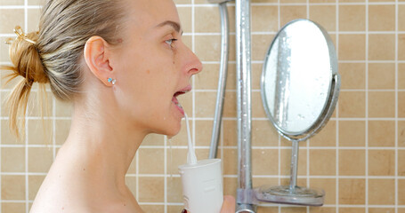 Young woman cleaning her teeth with brace by oral irrigator.
