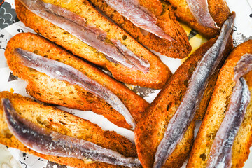 Crispy toasts with anchovies on a plate.