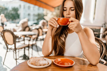 Portrait of happy woman sitting in a cafe outdoor drinking coffee. Woman while relaxing in cafe at...