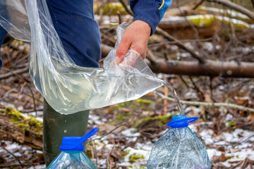 A transparent cellophane bag with birch sap is poured into a bottle