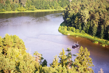 Two cable cars on the background of the river and green forest - obrazy, fototapety, plakaty